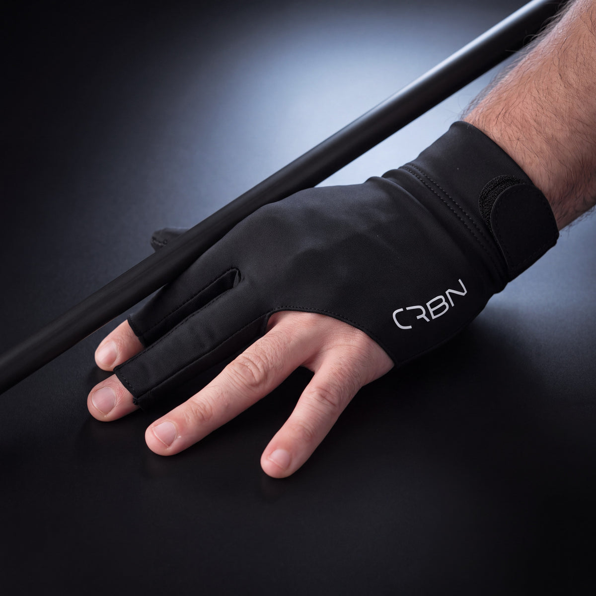 CRBN Cues glove worn on a bridge hand resting on a cue shaft, fingertips open